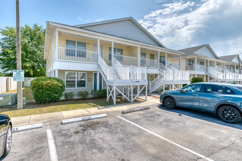A car is parked in a parking lot in front of a building with a sign that says "STAFF PARKING".