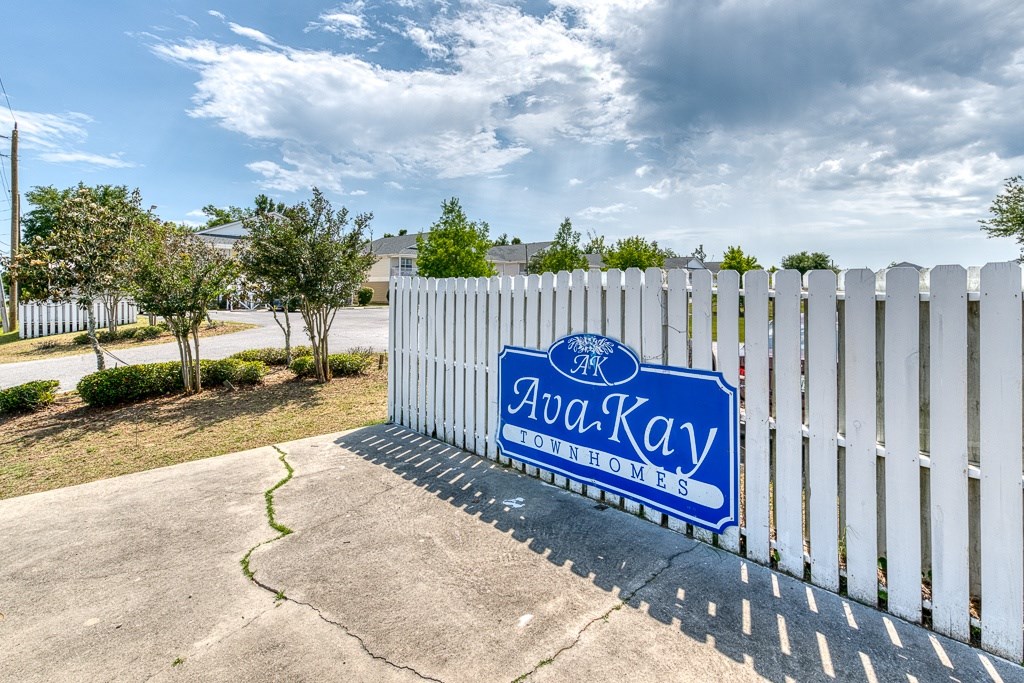 A white fence with a blue sign that says AvaKay Townhomes.