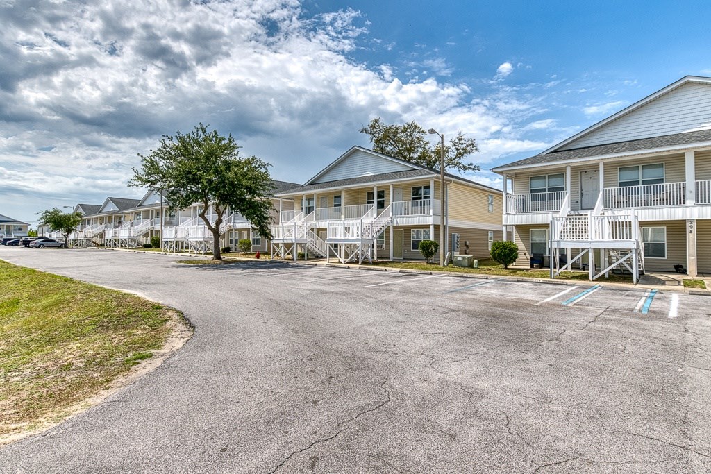 A road in front of apartment buildings with a tree on the left.