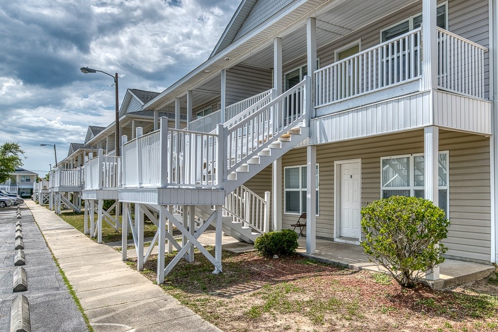 A row of houses with white railings and steps leading to the doors.