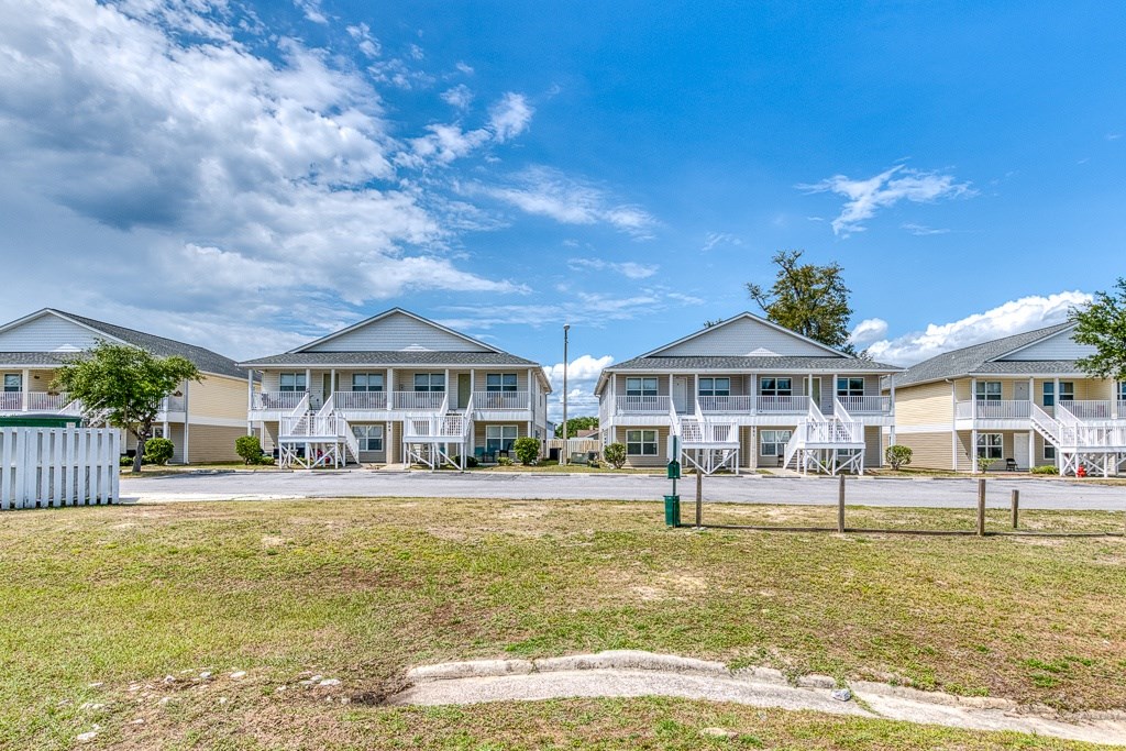 A row of houses with white lawn chairs in front.