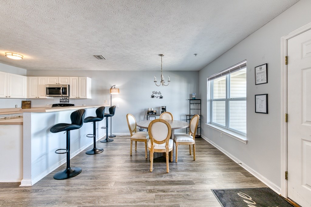 A kitchen with a bar area and a dining table with chairs.