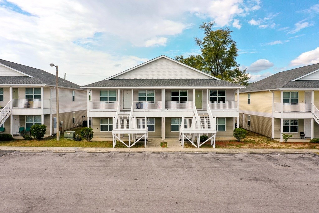 A row of identical houses with white porches and green lawns.