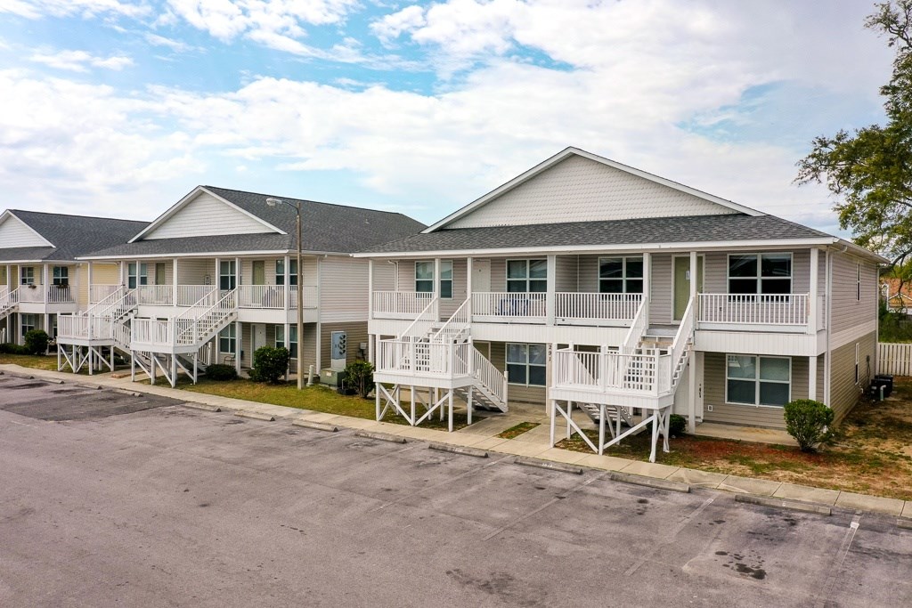 A row of white houses with porches and stairs leading to them.