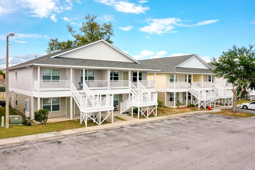 A two-story house with a white porch and a car parked in front.