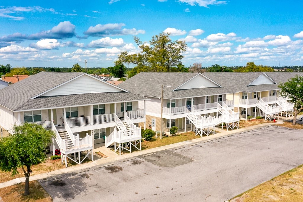 A row of houses with white balconies and a tree in front of one.