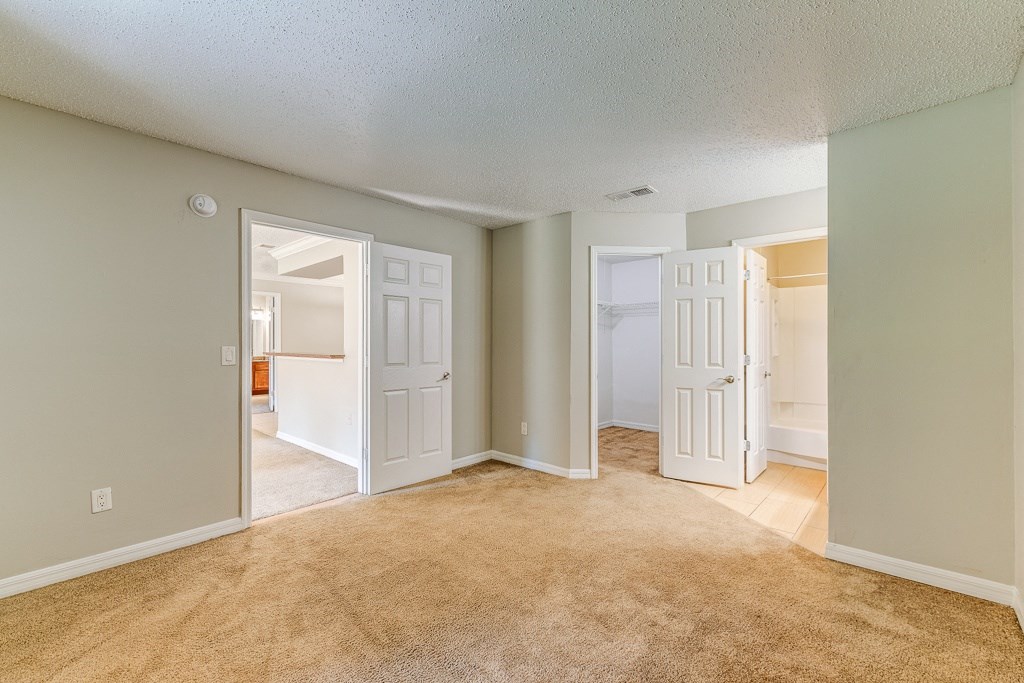 an empty living room with two open doors and a carpeted floor