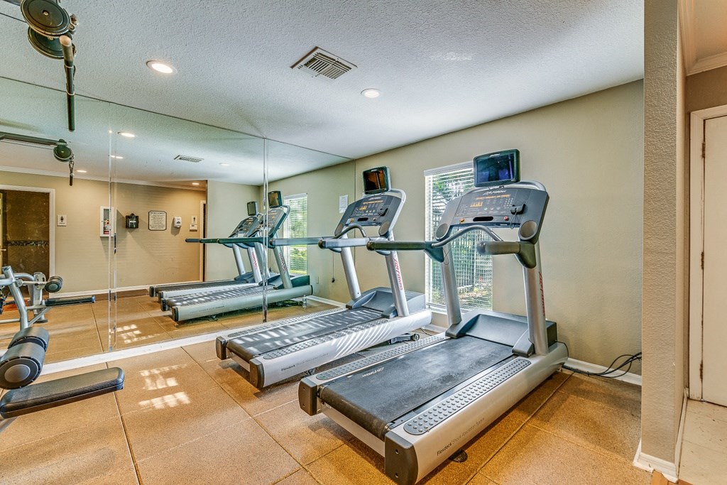 a gym with cardio equipment on the floor and mirrored walls