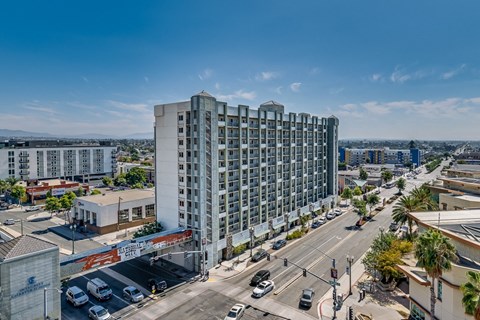 A large white building is in the middle of a city intersection.