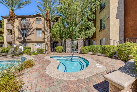a swimming pool with a fountain in front of an apartment building