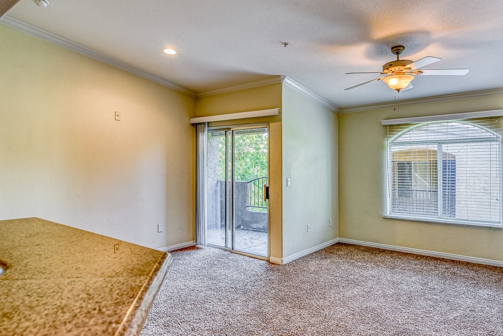 an empty living room with a ceiling fan and a door to a patio