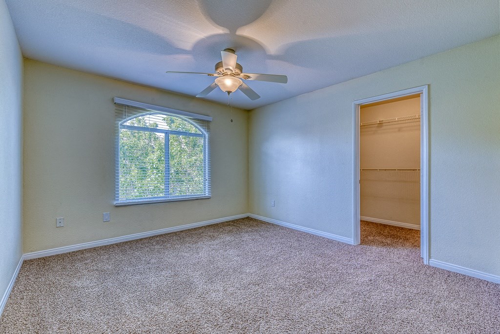 an empty room with a ceiling fan and a window