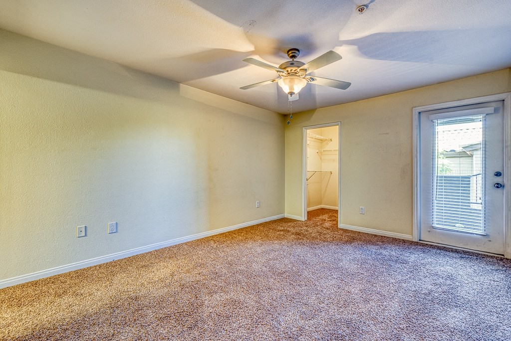 an empty room with a ceiling fan and a door to a closet