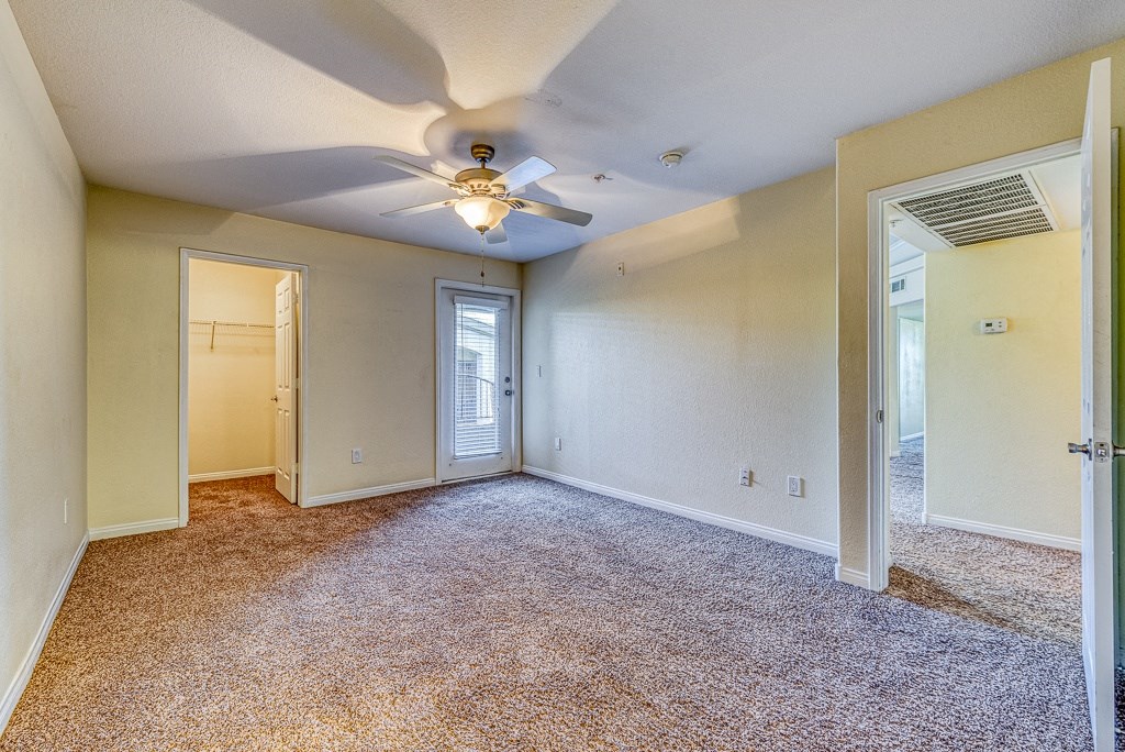 an empty living room with a ceiling fan and a door to a closet