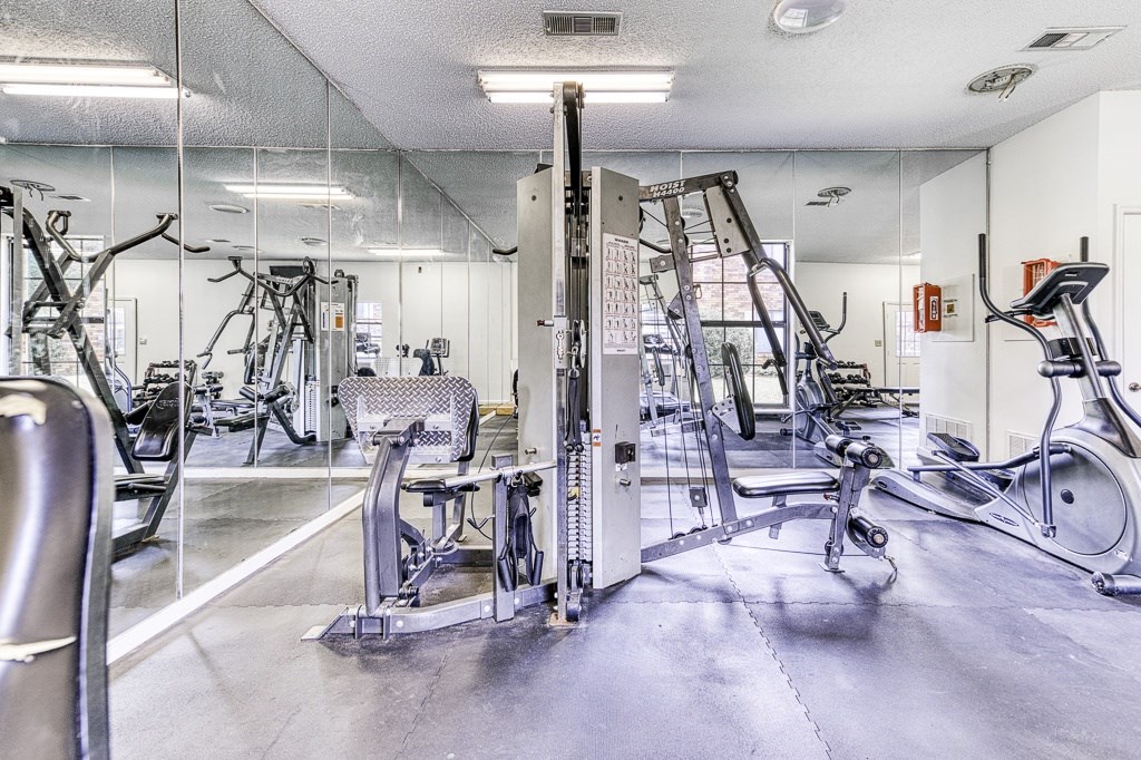 A gym with a variety of equipment including treadmills, weights, and exercise machines.