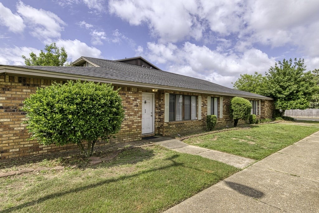 A brick house with a white door and windows.