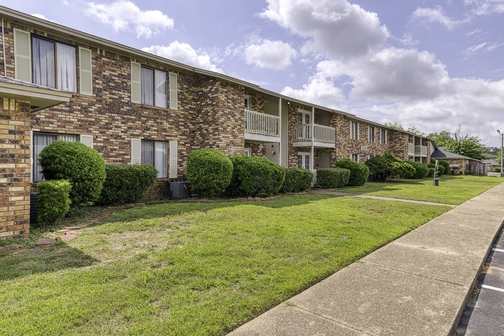 A row of apartment buildings with green lawns in front.