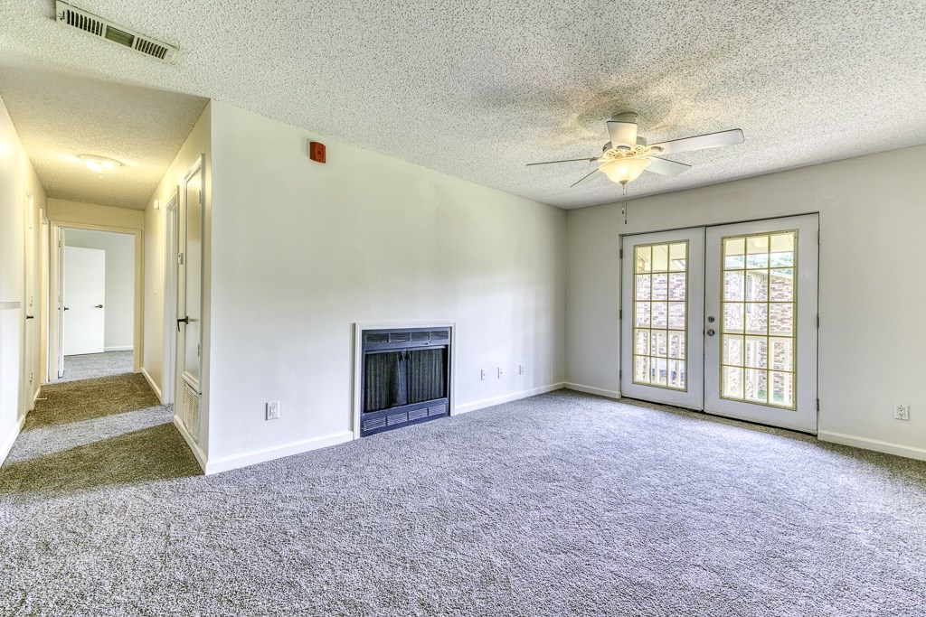 A living room with a fireplace and a ceiling fan.