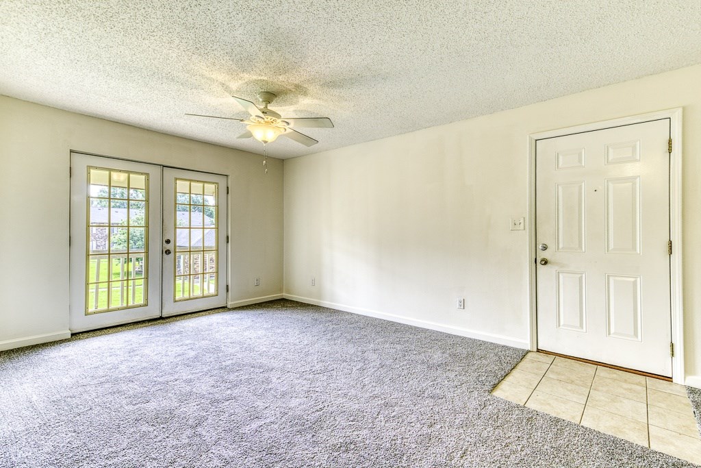 A room with a ceiling fan and two doors.