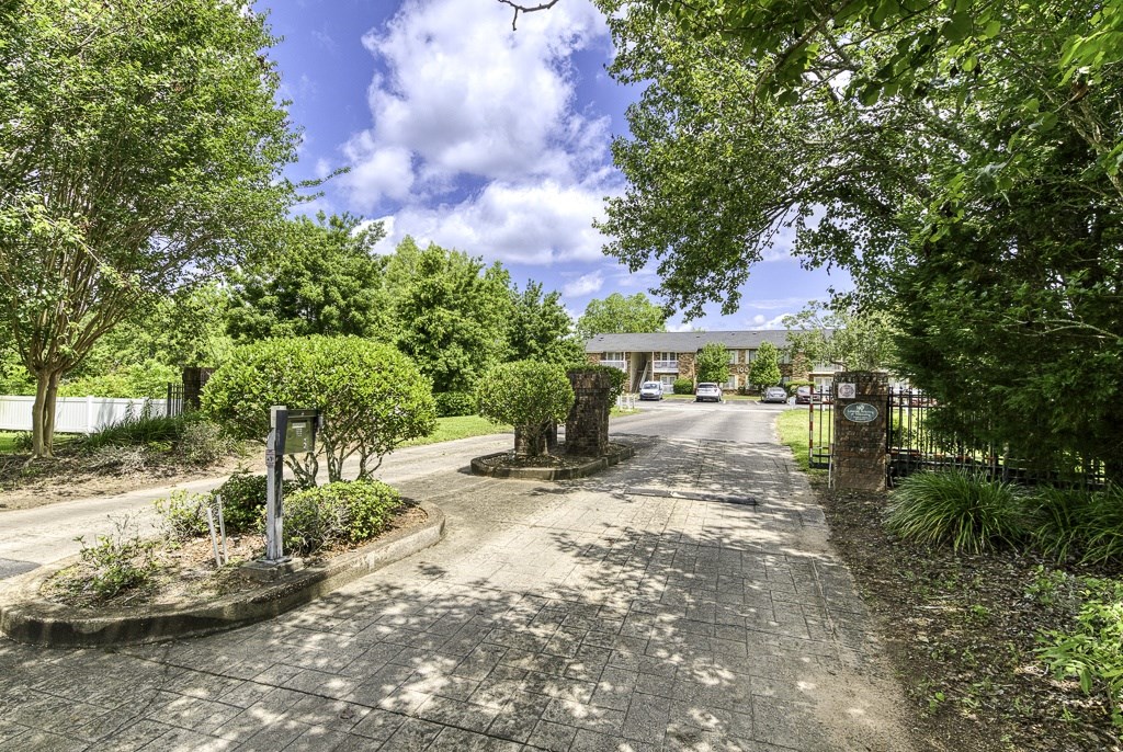 A tree-lined pathway leads to a building.