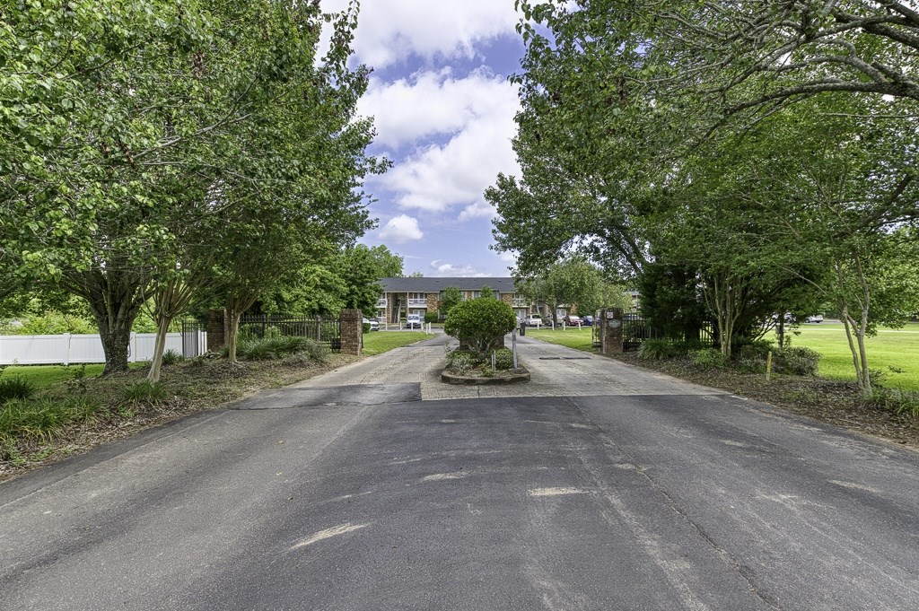A road with trees on both sides leading to a building.