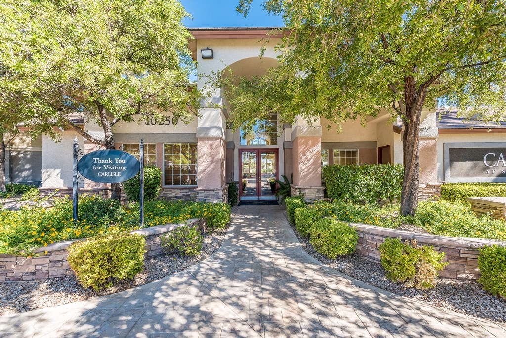 a building with a sidewalk and trees in front of it