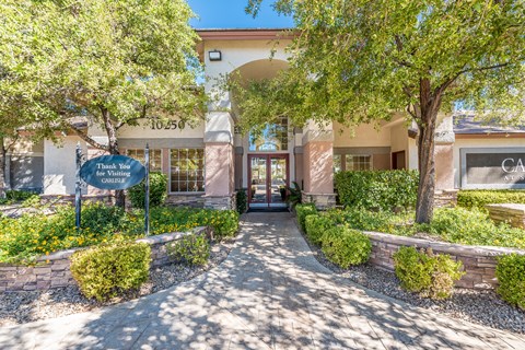 a building with a sidewalk and trees in front of it