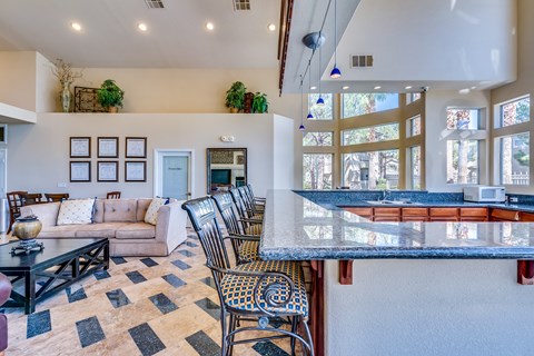 the living room and kitchen of a house with a bar and couches