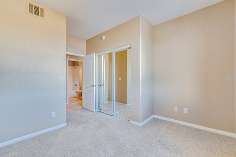 an empty bedroom with mirrored closet doors and carpeting