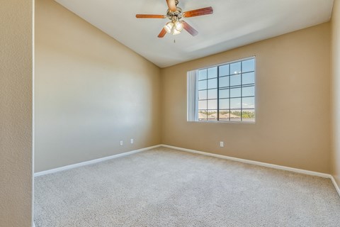an empty living room with a ceiling fan and a window
