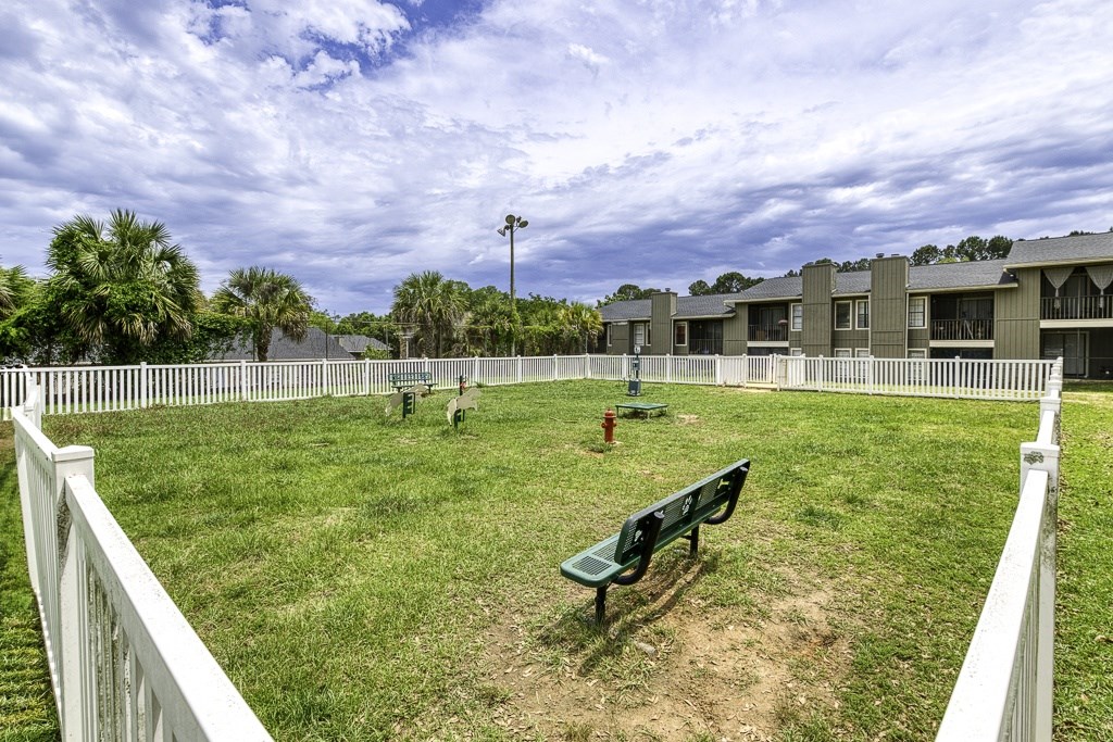 A park with a white fence and a green bench.