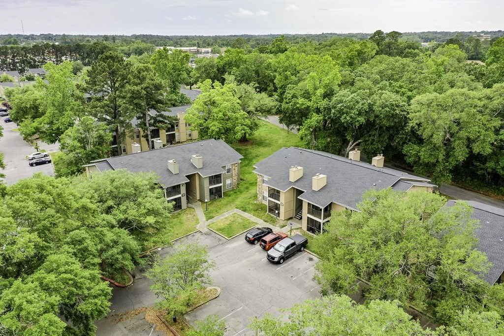 A bird's eye view of a parking lot with cars and a building with a grey roof.