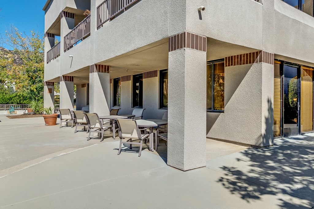 A modern building with a balcony and a table and chairs outside.