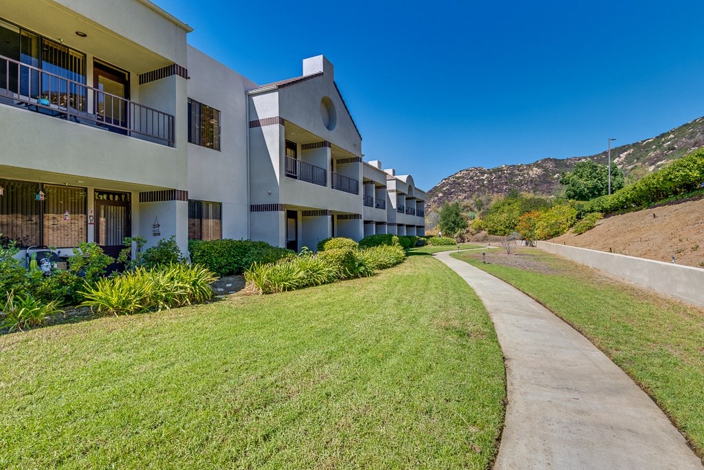 A concrete pathway leads through a grassy area in front of apartment buildings.