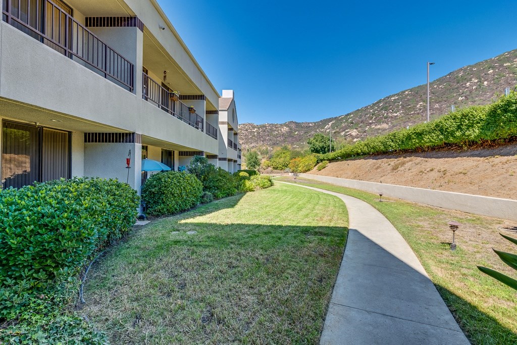 A building with a balcony overlooks a grassy area with a mountain in the background.