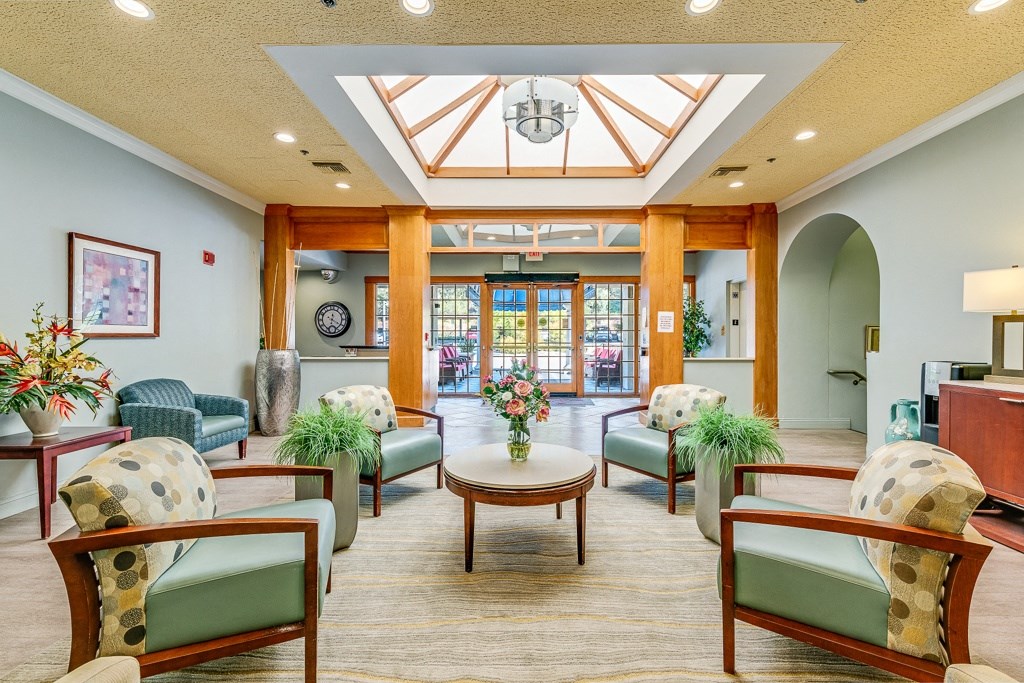 A spacious waiting room with wooden furniture and a skylight.