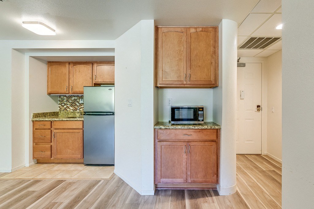 A kitchen with wooden cabinets and a stainless steel refrigerator.
