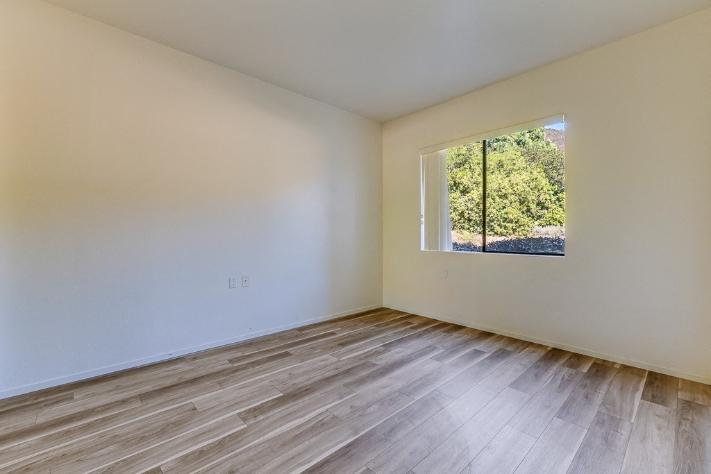 Empty room with wooden flooring and a window.