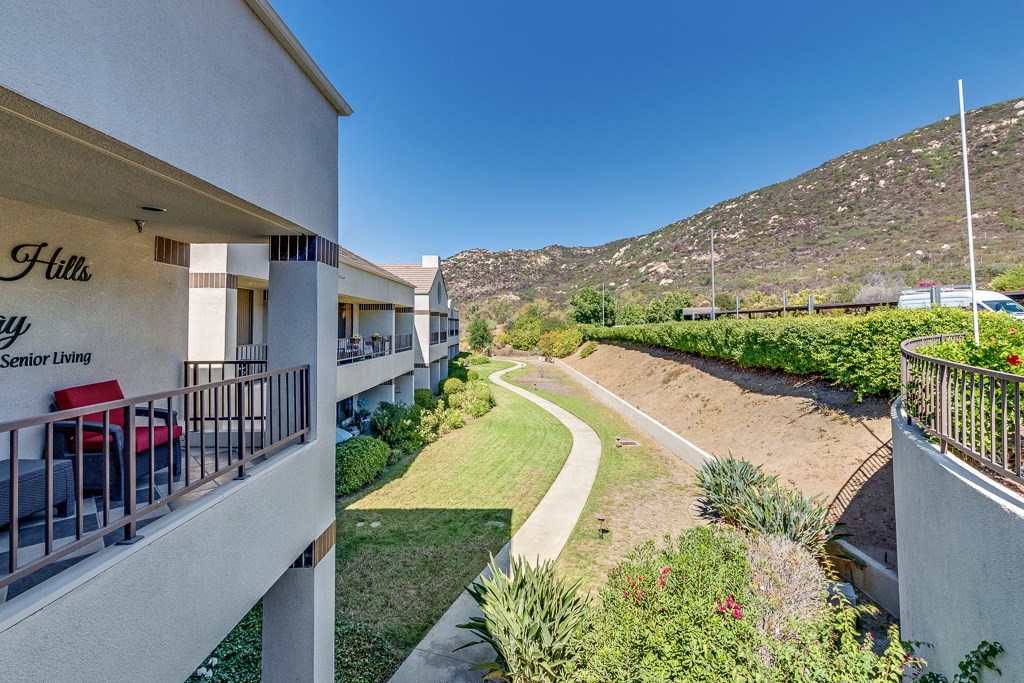 A view of a balcony overlooking a pathway and a grassy area at the Hill's Senior Living.