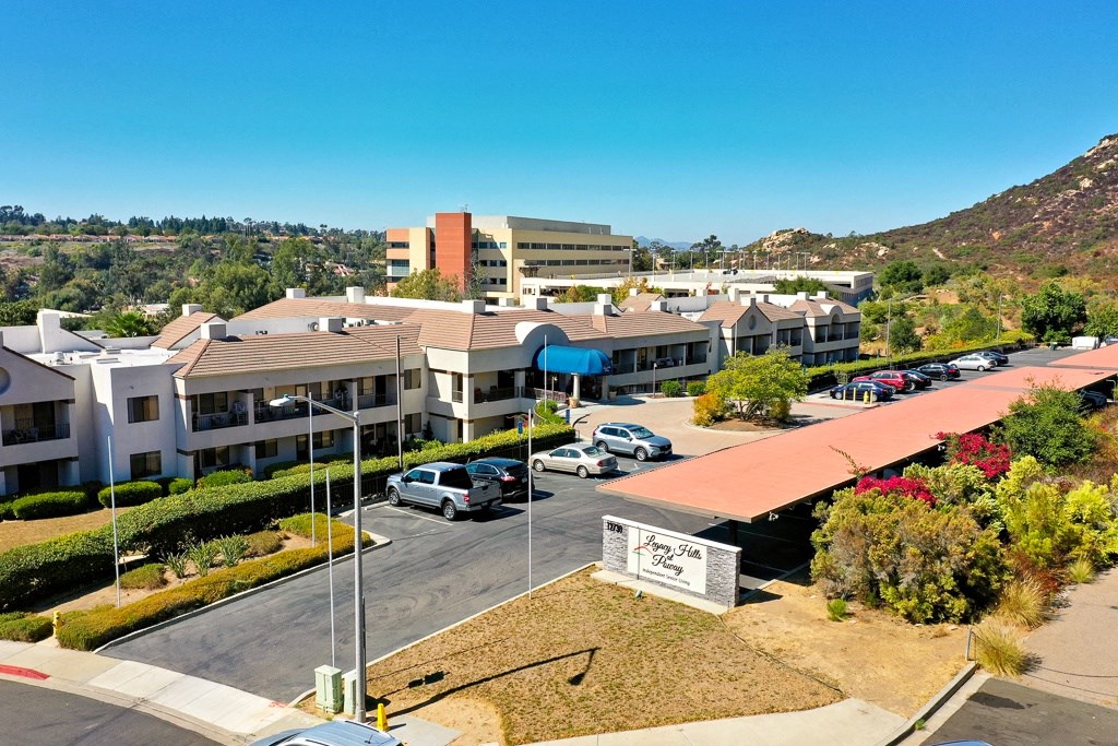 A sunny day at the residential complex with cars parked and buildings in the background.