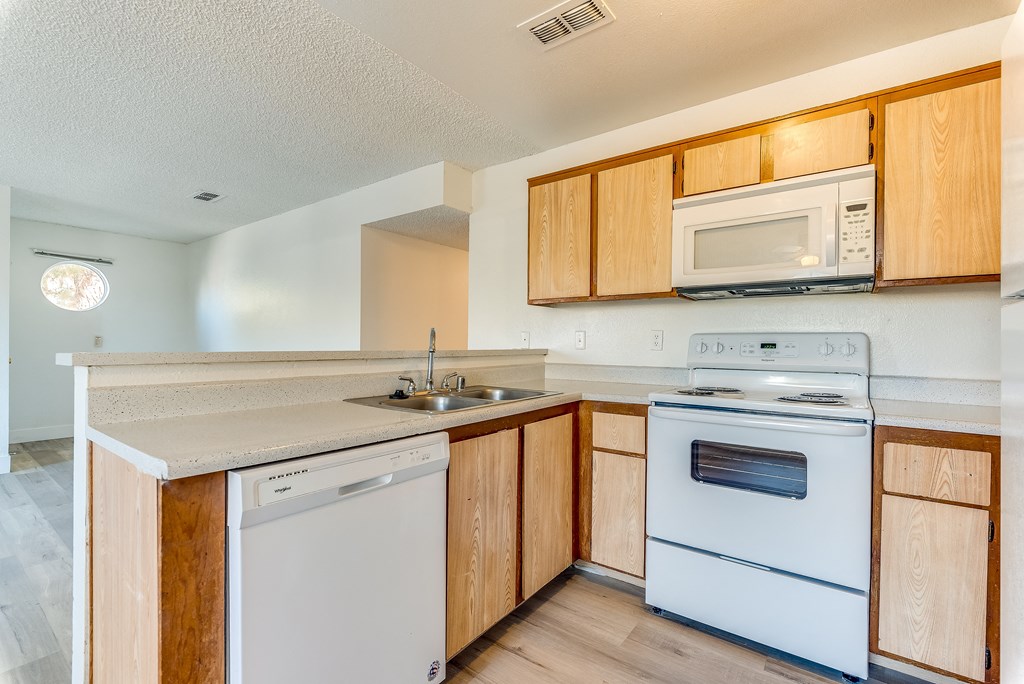 a kitchen with wooden cabinets and white appliances at Pacific Harbors Sunrise Apartments, Las Vegas, NV