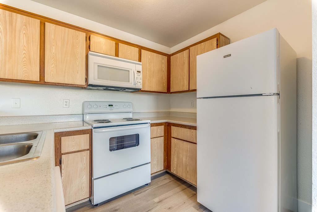 a kitchen with white appliances and wooden cabinets at Pacific Harbors Sunrise Apartments, Las Vegas, NV