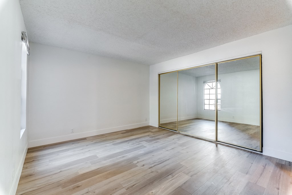 a bedroom with hardwood floors and a large mirror at Pacific Harbors Sunrise Apartments, Las Vegas, NV, 89142