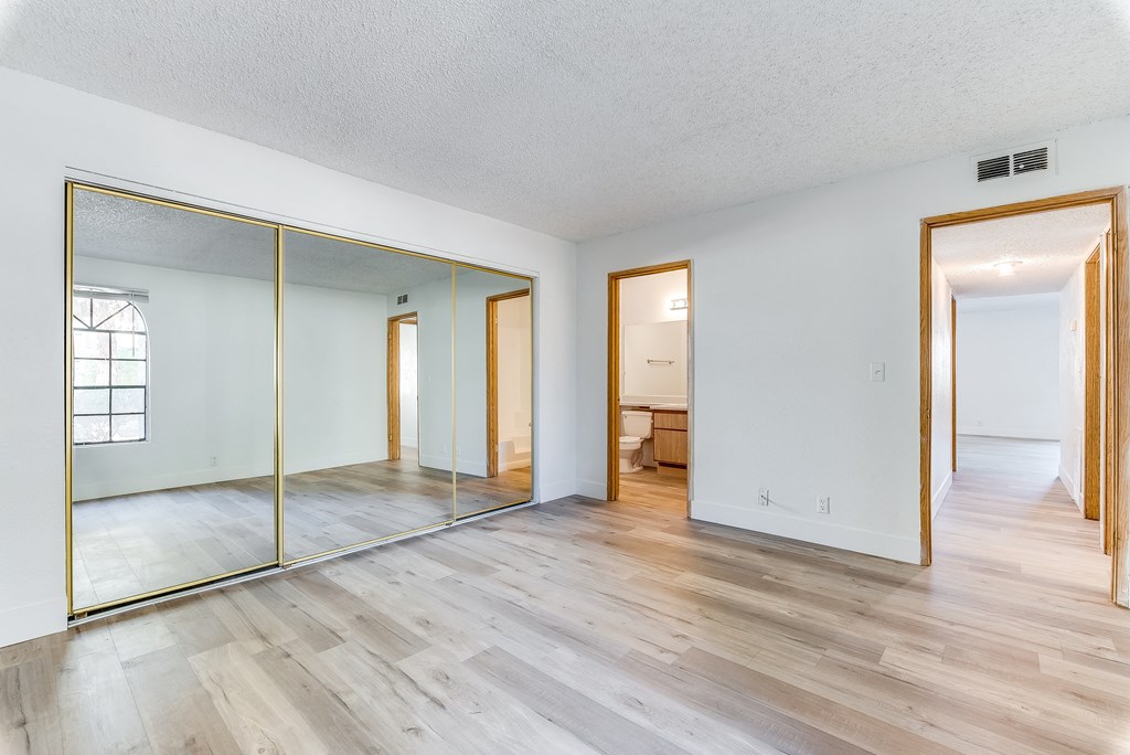 a bedroom with hardwood floors and a large mirror at Pacific Harbors Sunrise Apartments, Las Vegas, Nevada