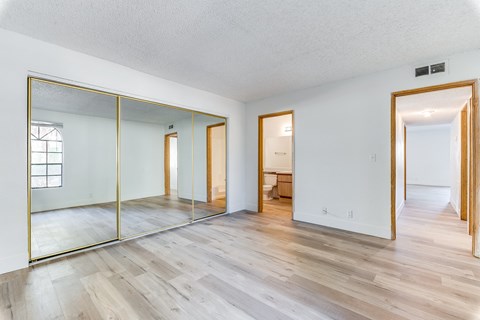 Bedroom with hardwood floors and large mirror at Pacific Harbors Sunrise Apartments, Las Vegas
