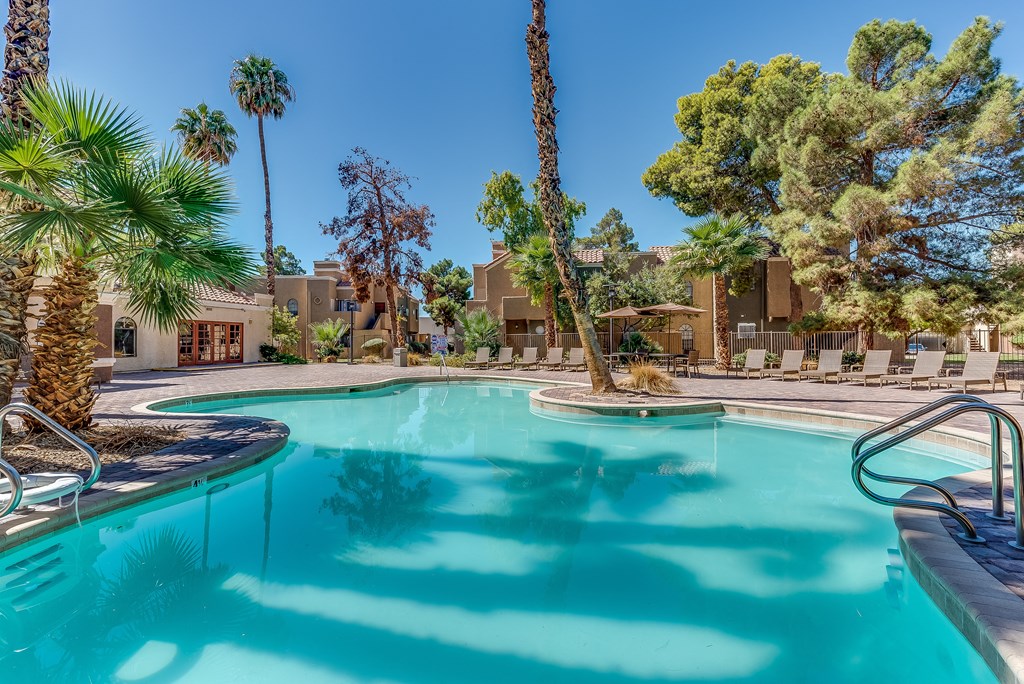 a swimming pool with palm trees and a building in the background at Pacific Harbors Sunrise Apartments, Las Vegas, NV, 89142