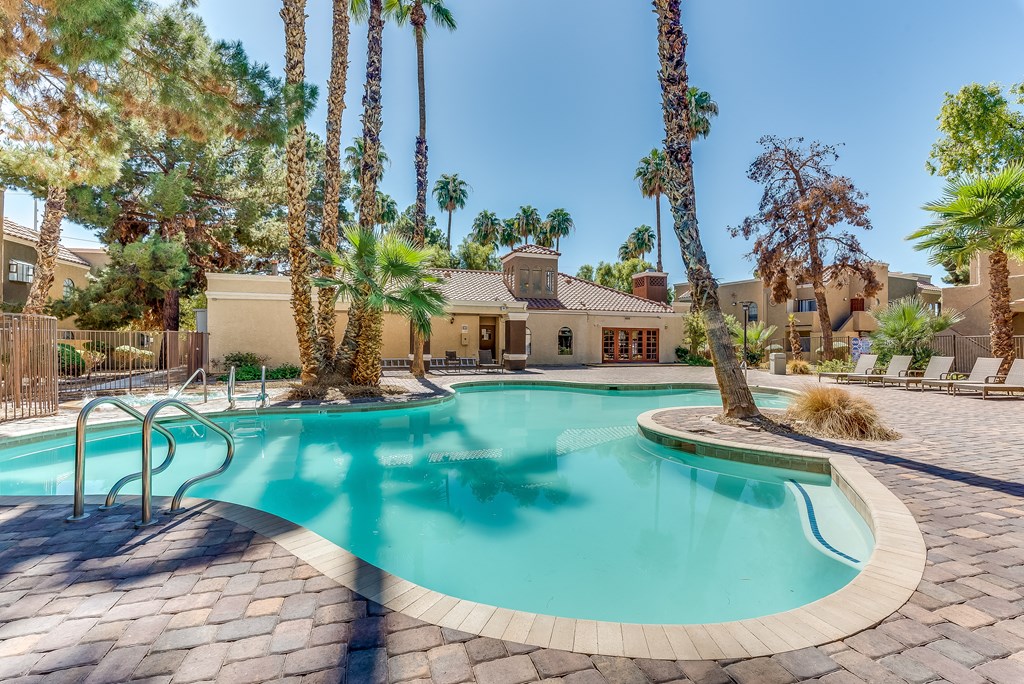 a swimming pool with palm trees and a house in the background at Pacific Harbors Sunrise Apartments, Las Vegas, NV, 89142