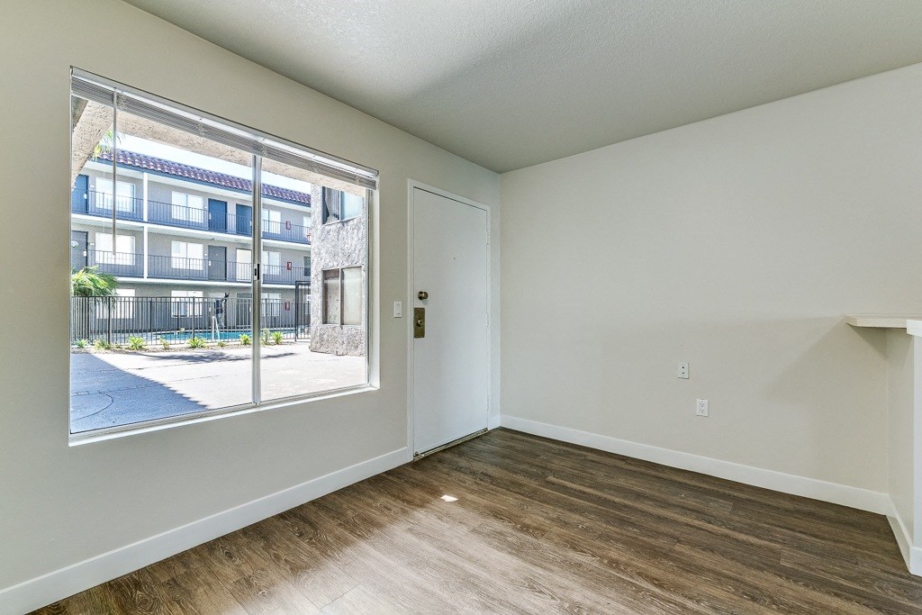 an empty living room with a large window and wood flooring