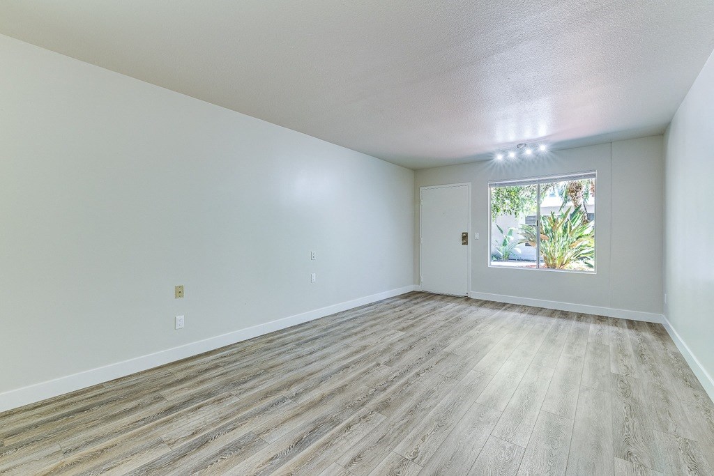 an empty living room with wood floors and a window