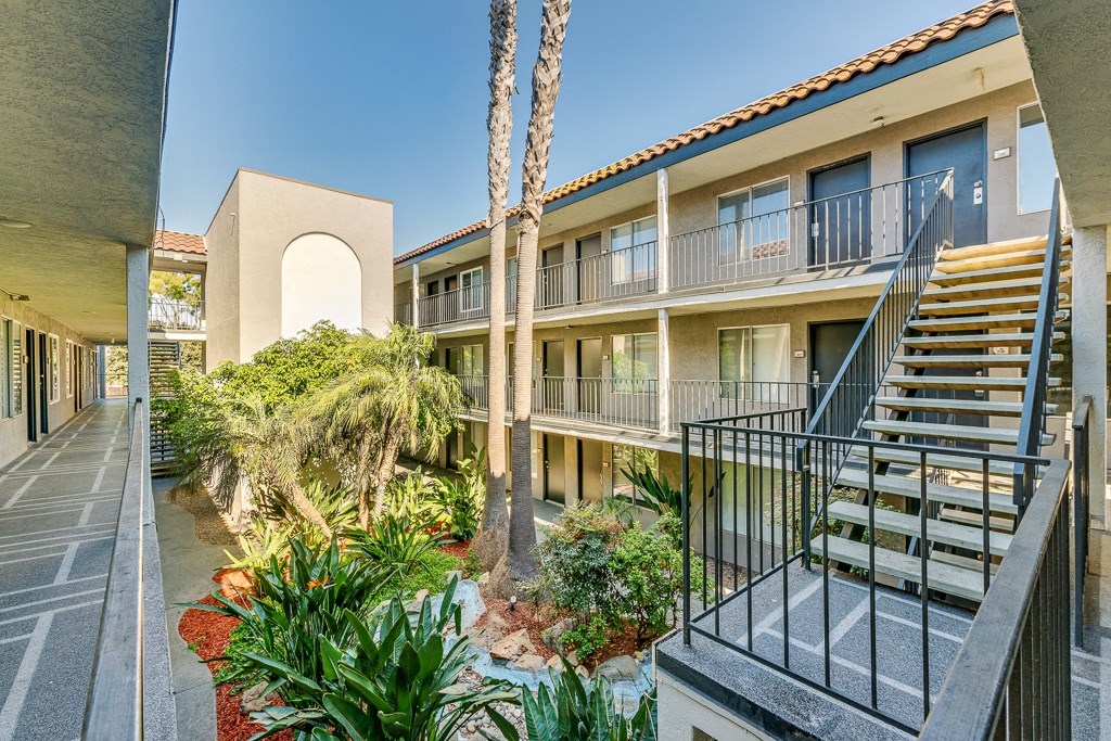 a building with stairs and a courtyard with palm trees
